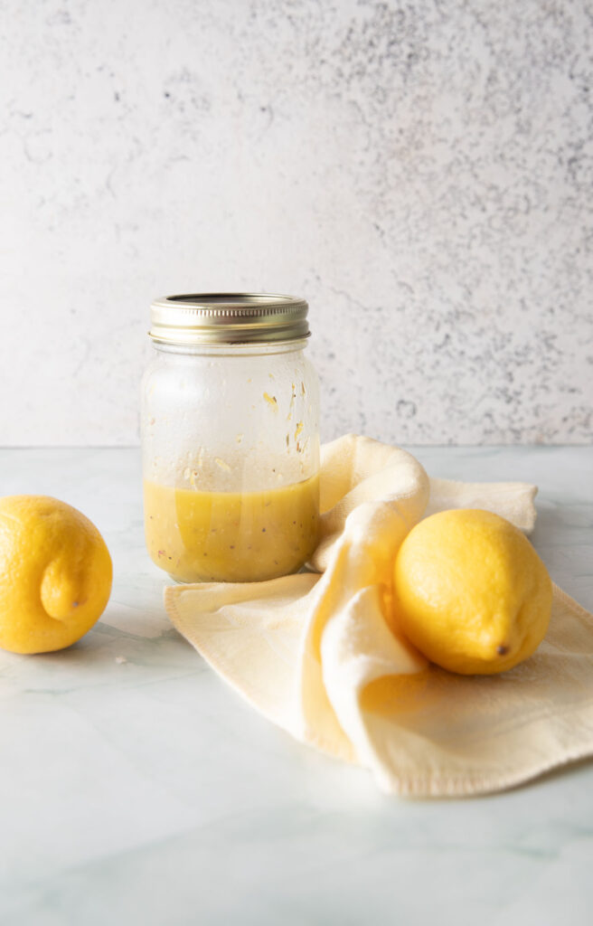 Jar of Honey Lemon Vinaigrette on a green board.