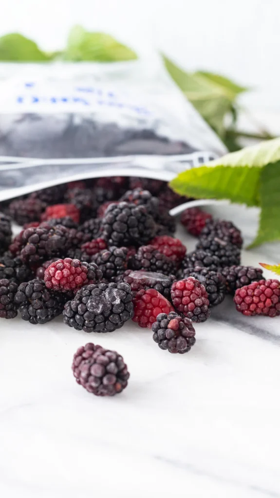 Frozen Blackberries spilling from plastic storage bag.