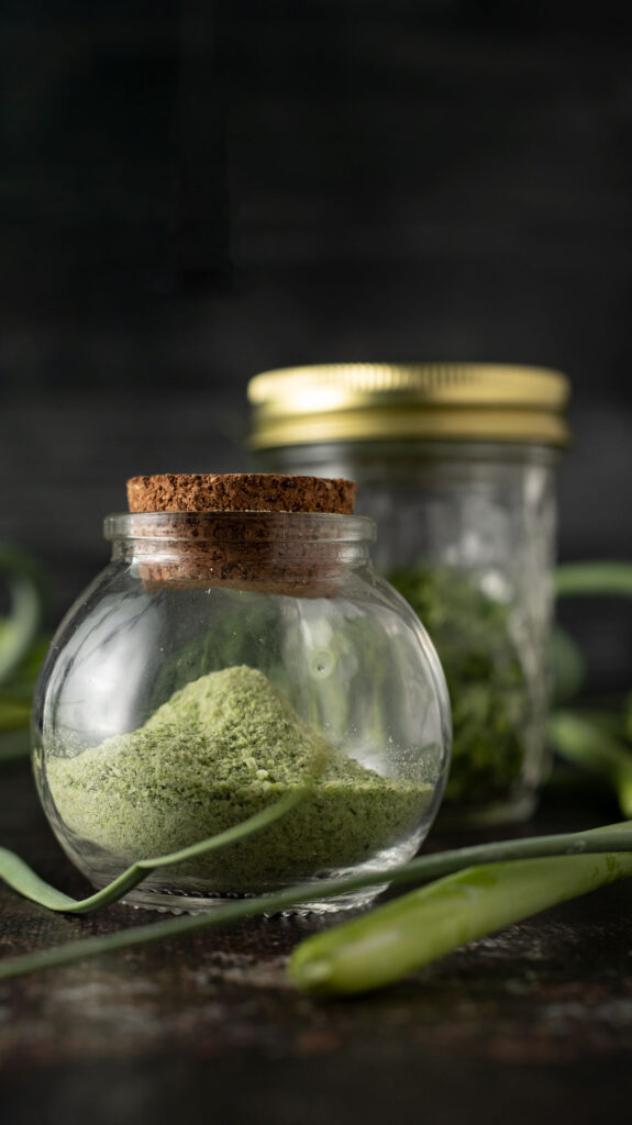 Dehydrated garlic scapes in a jar with fresh garlic scapes visible