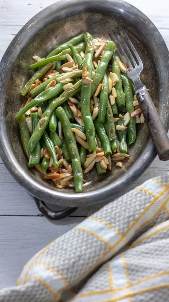 Green beans almondine in silver serving dish.