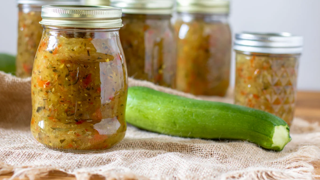 Zucchini relish in jars with a whole fresh zucchini.