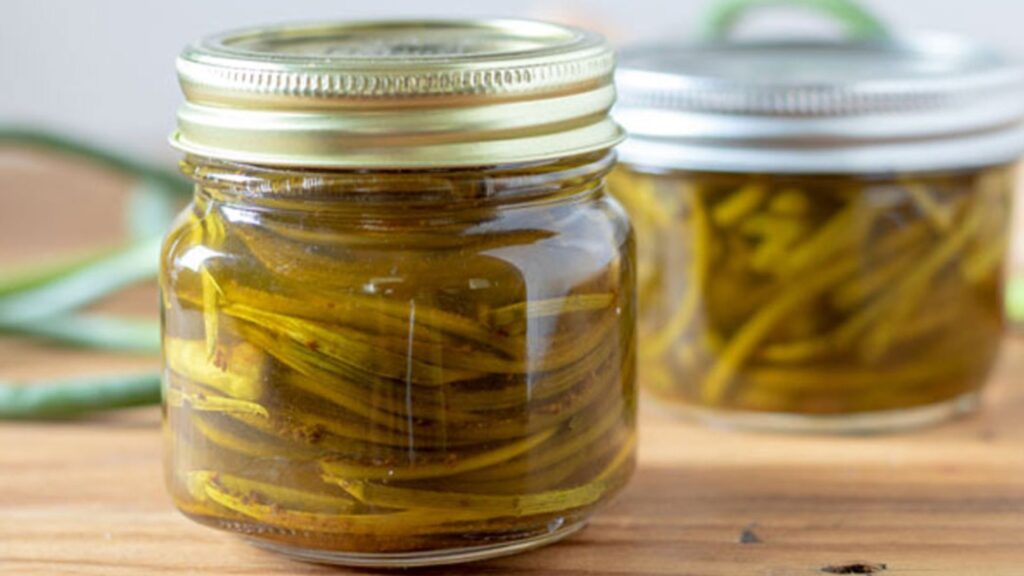 Pickled garlic scapes in half pint jars.