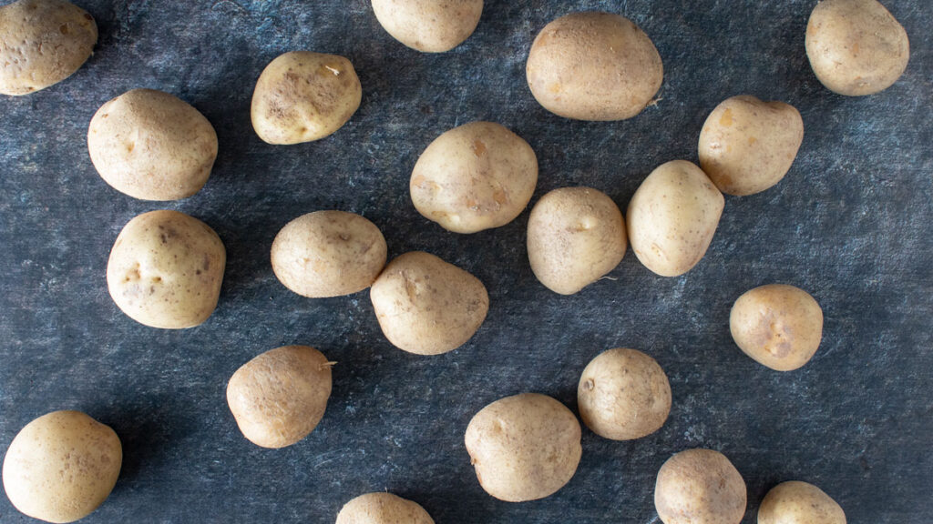 Fresh potatoes scattered on a black board.