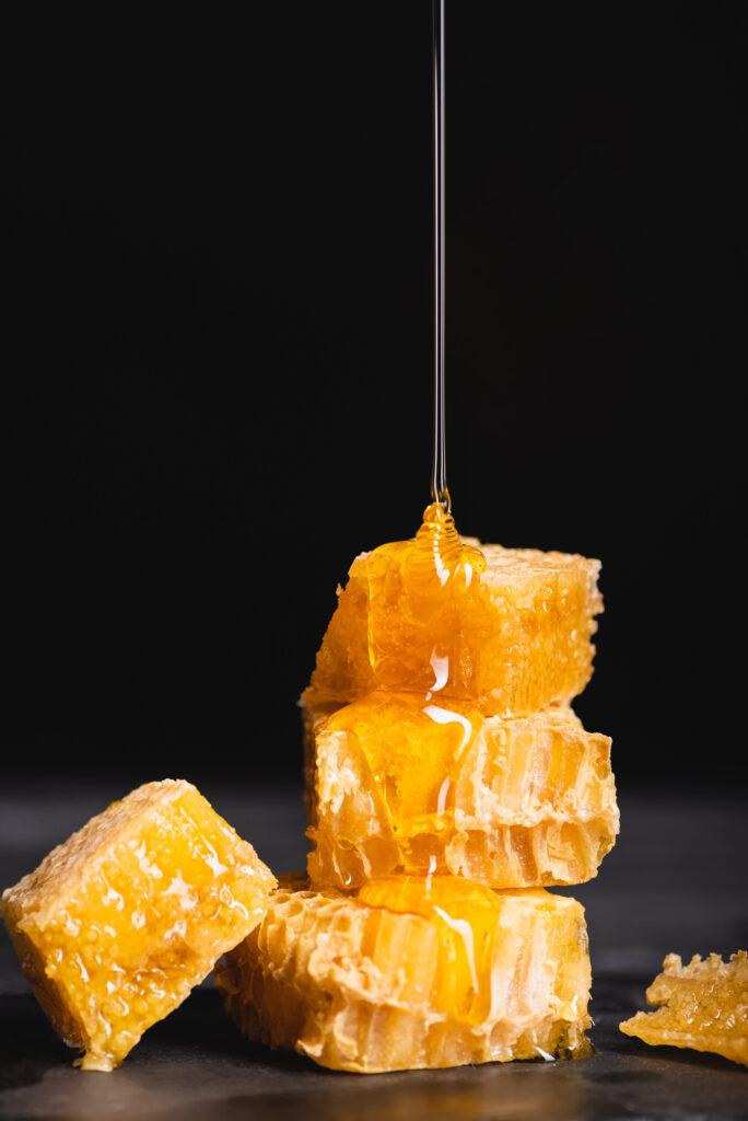 Honey dripping onto a stack of honeycomb squares.