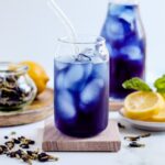 A glass of Butterfly Pea Tea on a coaster.