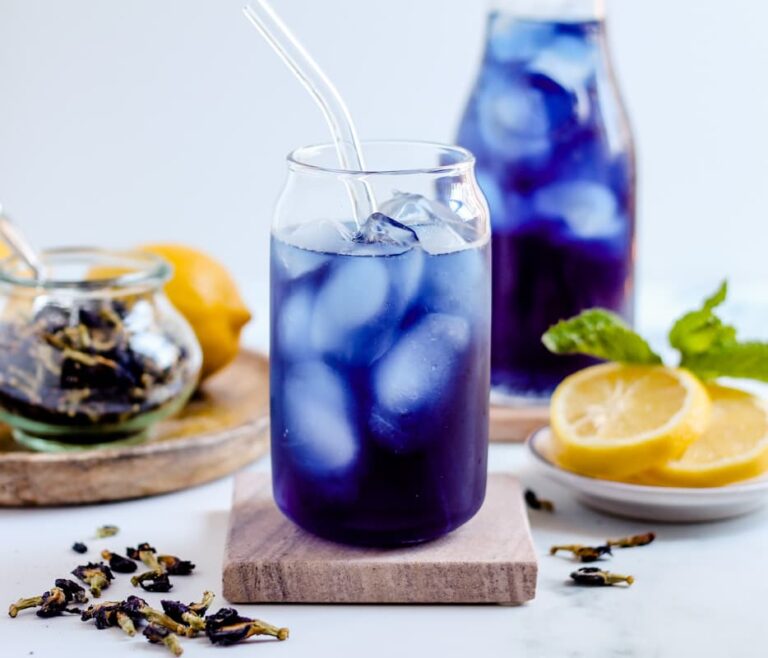 A glass of Butterfly Pea Tea on a coaster.